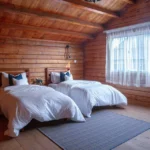wooden bed and breakfast room with two large beds next to a window
