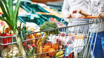 A couple shopping for groceries and pushing a trolley cart